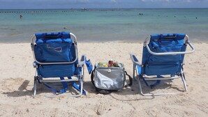 Two beach chairs with a bag between them on a sandy beach. - Casa De Namaste- Relaxing 1 Br Condo near Playa's best Beaches & 5th Ave! (Playa del Carmen)