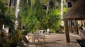 A nighttime outdoor area with palm trees, lounge chairs, and a thatched-roof structure. - Casa De Namaste- Relaxing 1 Br Condo near Playa's best Beaches & 5th Ave! (Playa del Carmen)