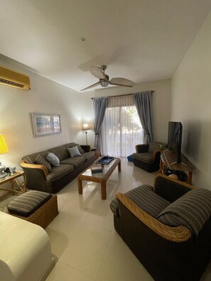 A living room with a ceiling fan, two sofas, a coffee table, a TV, and a lamp.
