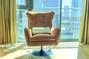 A modern armchair with a cushioned seat and backrest, positioned in front of a large window with a cityscape view.