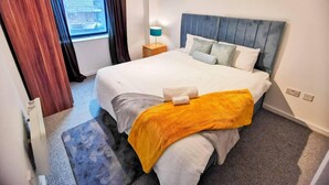 Une chambre d’hôtel avec un grand lit, une table de chevet avec une lampe, une fenêtre avec des rideaux et une vue sur la ville.