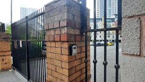 Une entrée fermée par un portail, avec un mur en briques et un portail en métal.