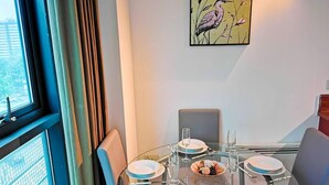Un coin repas avec une table ronde en verre, quatre chaises et un tableau accroché au mur.