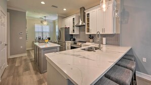 A modern kitchen with white cabinets, a marble island, and a built-in stove.