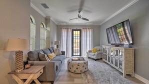 A living room with a sofa, ottoman, TV, and a cabinet.
