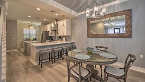 A modern kitchen with a central island, bar stools, and a dining table with chairs.