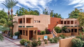 A modern building with multiple floors, surrounded by landscaped gardens and palm trees. - Club Wyndham Orange Tree Resort (Scottsdale)