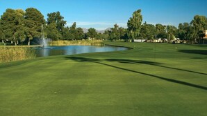 A well-maintained golf course with a pond, trees, and a clear sky. - Club Wyndham Orange Tree Resort (Scottsdale)