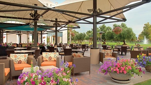 An outdoor patio area with wicker furniture, large umbrellas, and potted flowers. - Club Wyndham Orange Tree Resort (Scottsdale)