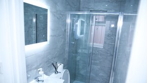 Un bagno moderno con cabina doccia in vetro, un lavandino bianco e un water.