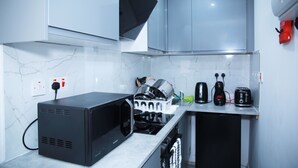 Una cucina compatta con forno a microonde, tostapane e macchina del caffè sul piano di lavoro.