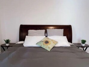 Cozy retreat with a comfortable bed, bedside tables, and potted plants.