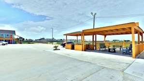 A covered outdoor area with a bench and chairs, a small table, and a pathway leading to a building. - Monterrey Motel Padre Island, Corpus Christi By Oyo (Corpus Christi)