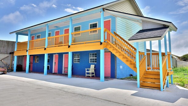 A two-story building with a covered porch and a staircase. - Monterrey Motel Padre Island, Corpus Christi By Oyo (Corpus Christi)
