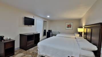 Habitación de hotel con dos camas, televisor, escritorio con cafetera y espejo.