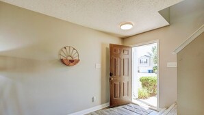 A hallway with a wooden door, a wall-mounted basket, and a light fixture. - 5 Mins to Ruoff+Dog Friendly+Fenced yard+Fast WiFi (Noblesville)