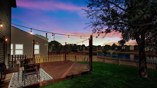 A wooden deck with outdoor furniture, a wooden fence, and a pond. - 5 Mins to Ruoff+Dog Friendly+Fenced yard+Fast WiFi (Noblesville)