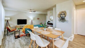A modern living room with a dining area, a flat-screen TV, and a large painting on the wall. - 5 Mins to Ruoff+Dog Friendly+Fenced yard+Fast WiFi (Noblesville)