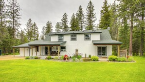 A two-story house with a covered porch, surrounded by a well-maintained lawn and tall trees. - 10 Mi to Silverwood: Secluded Getaway! (Spirit Lake)