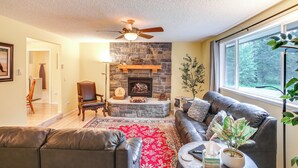 A living room with a stone fireplace, leather furniture, a red rug, and a large window. - 10 Mi to Silverwood: Secluded Getaway! (Spirit Lake)