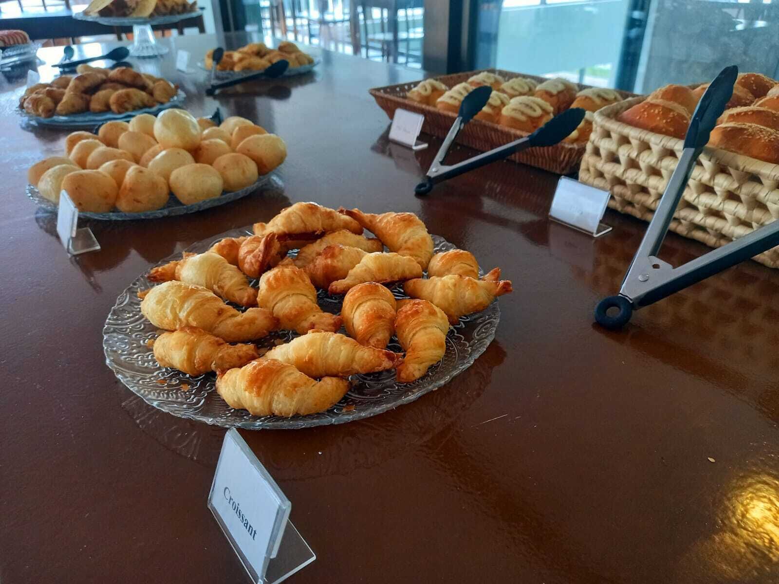 Et udvalg af friskbagte brød og kager på en disk, herunder croissanter og rundstykker.