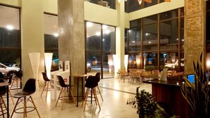 A spacious indoor area with high ceilings, large windows, and modern lighting fixtures. - Ilusion Flats Aconchego de Ponta Negra (Natal)