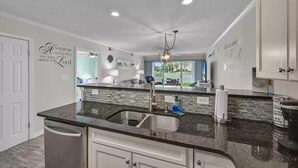 Een moderne keuken met een granieten aanrecht, een roestvrijstalen spoelbak en een ingebouwde vaatwasser.