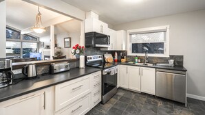 A modern kitchen with white cabinets, a stainless steel dishwasher, a microwave, and a stove.