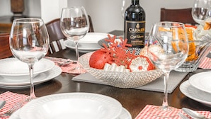 A dining table set with white plates, silverware, and wine glasses, with a bottle of Carmén wine and decorative items.