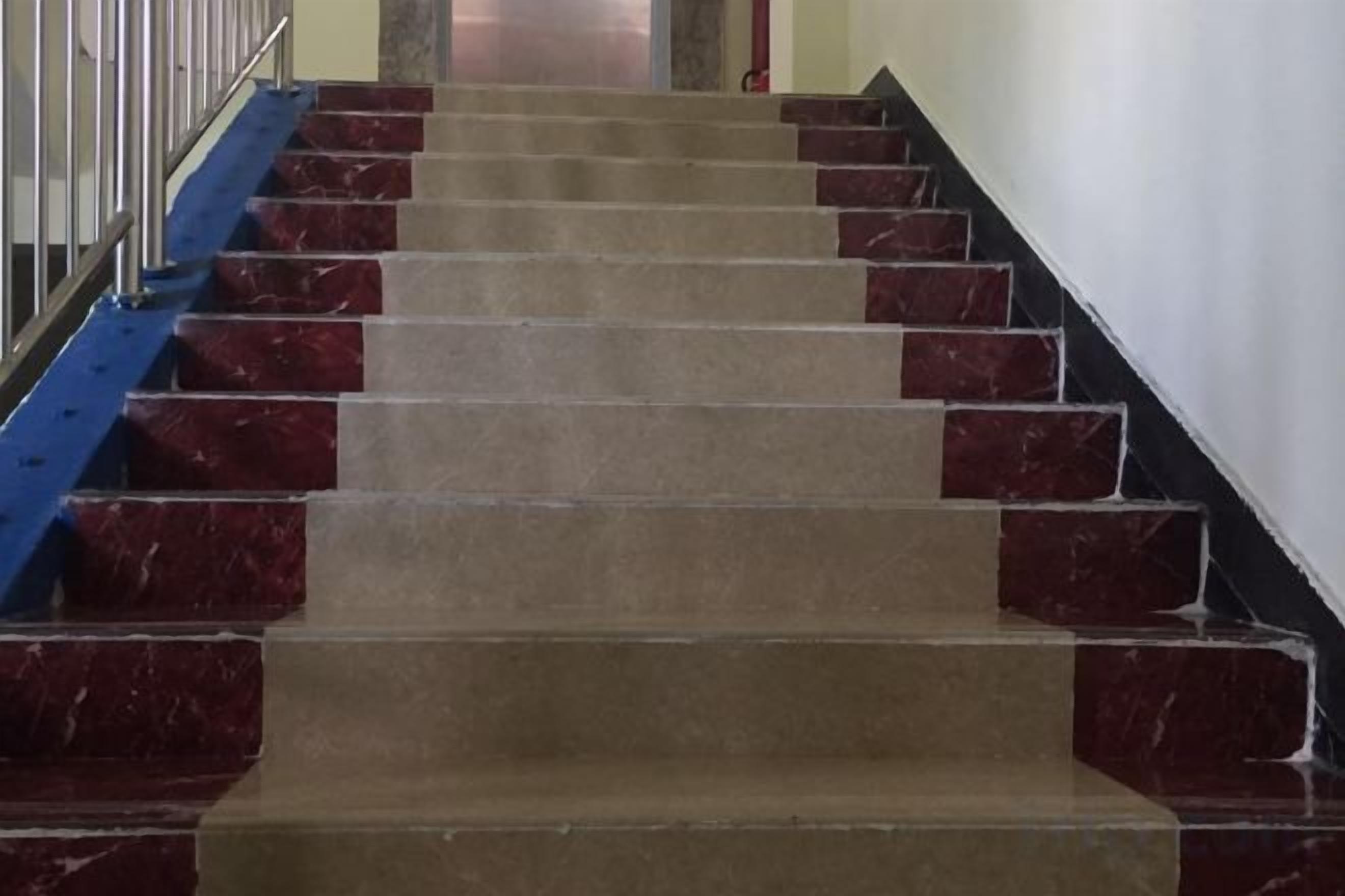 Una escalera con peldaños alternados en rojo y beige, que asciende.