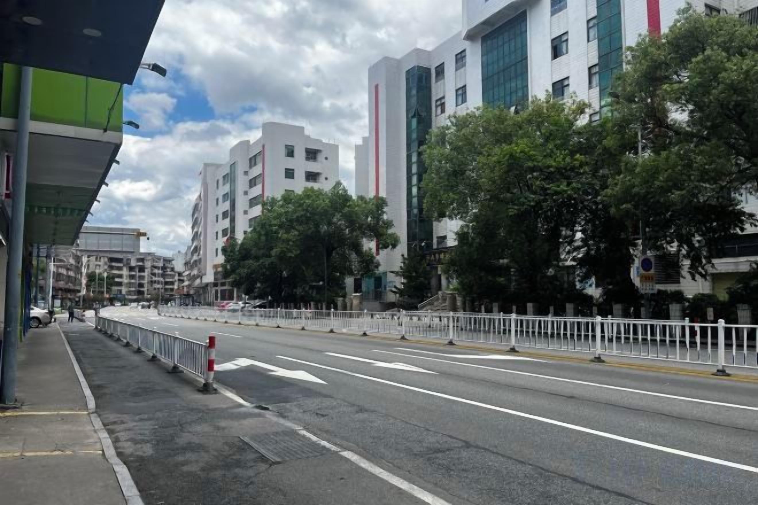 A city street with buildings, a clear sky, and a road with barriers.
