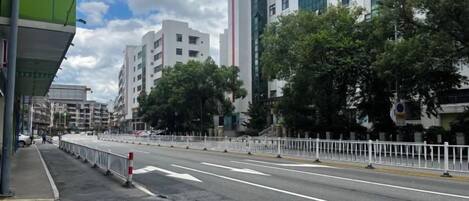 A city street with buildings, a clear sky, and a road with barriers.