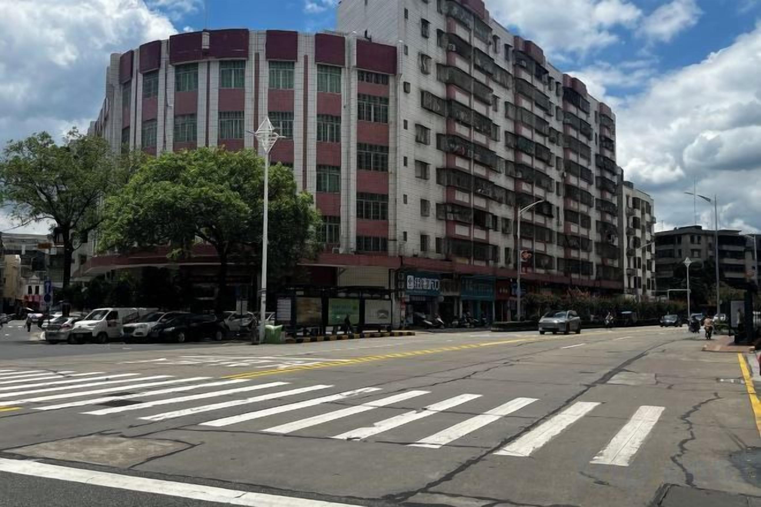 A multi-story building with a commercial ground floor, a crosswalk, and parked cars.