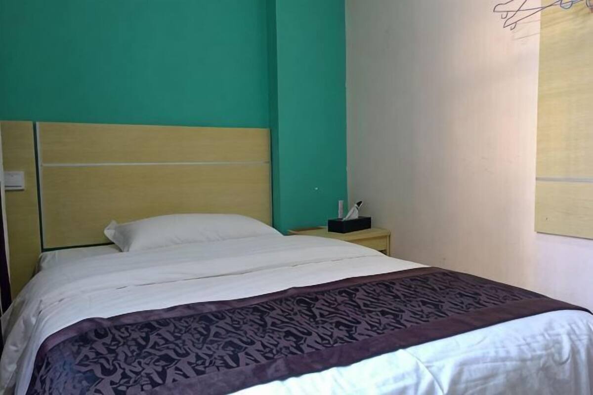 A bed with a headboard, a bedside table with a lamp, and a wall-mounted light fixture.