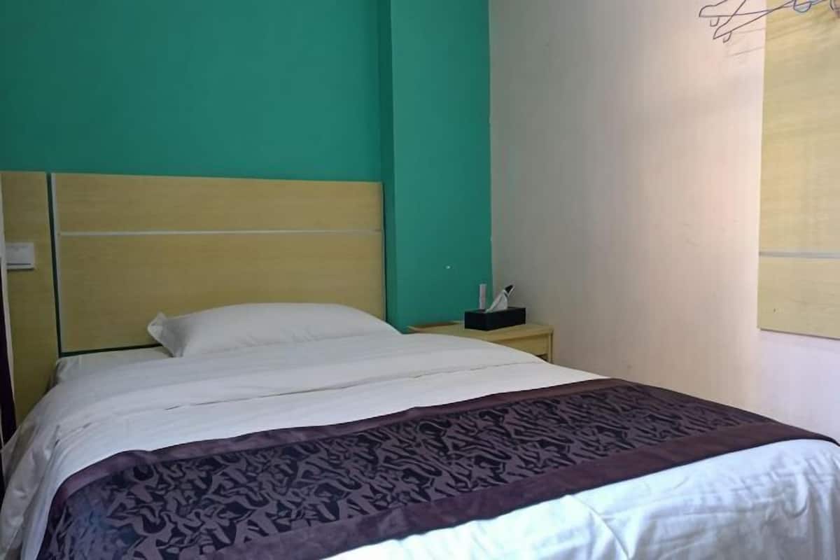A bed with a headboard, a bedside table with a lamp, and a wall-mounted light fixture.
