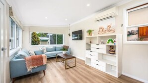 Een moderne woonkamer met een blauwe bank, een houten salontafel en witte opbergmeubels.
