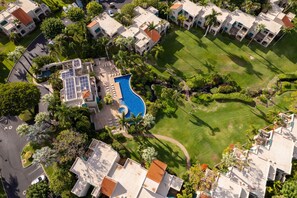 Vista aérea de una zona residencial con varios edificios, una piscina y céspedes bien cuidados.