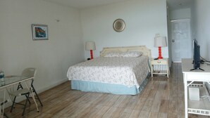 Une chambre à coucher avec un lit, deux tables de chevet avec des lampes, un bureau et une chaise.