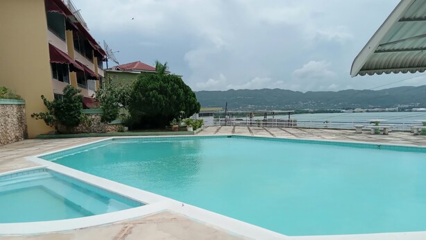 Une piscine avec vue sur les montagnes et un plan d’eau en arrière-plan.