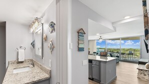 A modern kitchen with a granite countertop, a built-in dishwasher, and a large island. - Sandcastle Condominiums Unit 104 (Port Aransas)