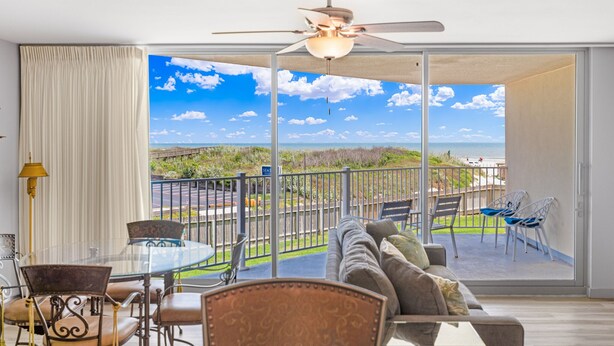 A room with a glass door leading to a balcony with a view of the beach. - Sandcastle Condominiums Unit 104 (Port Aransas)