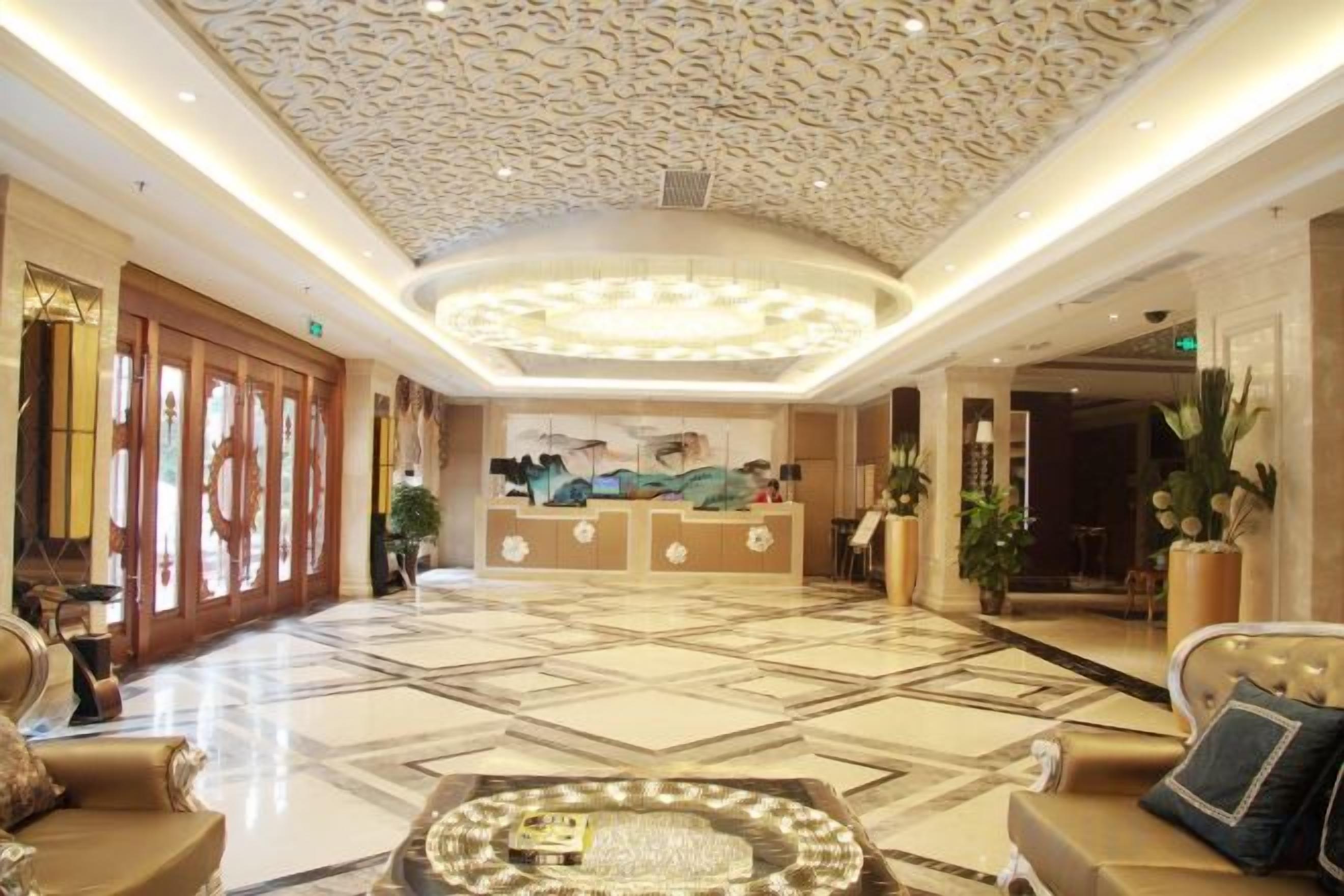 A hotel lobby with a reception desk, seating area, and decorative ceiling.