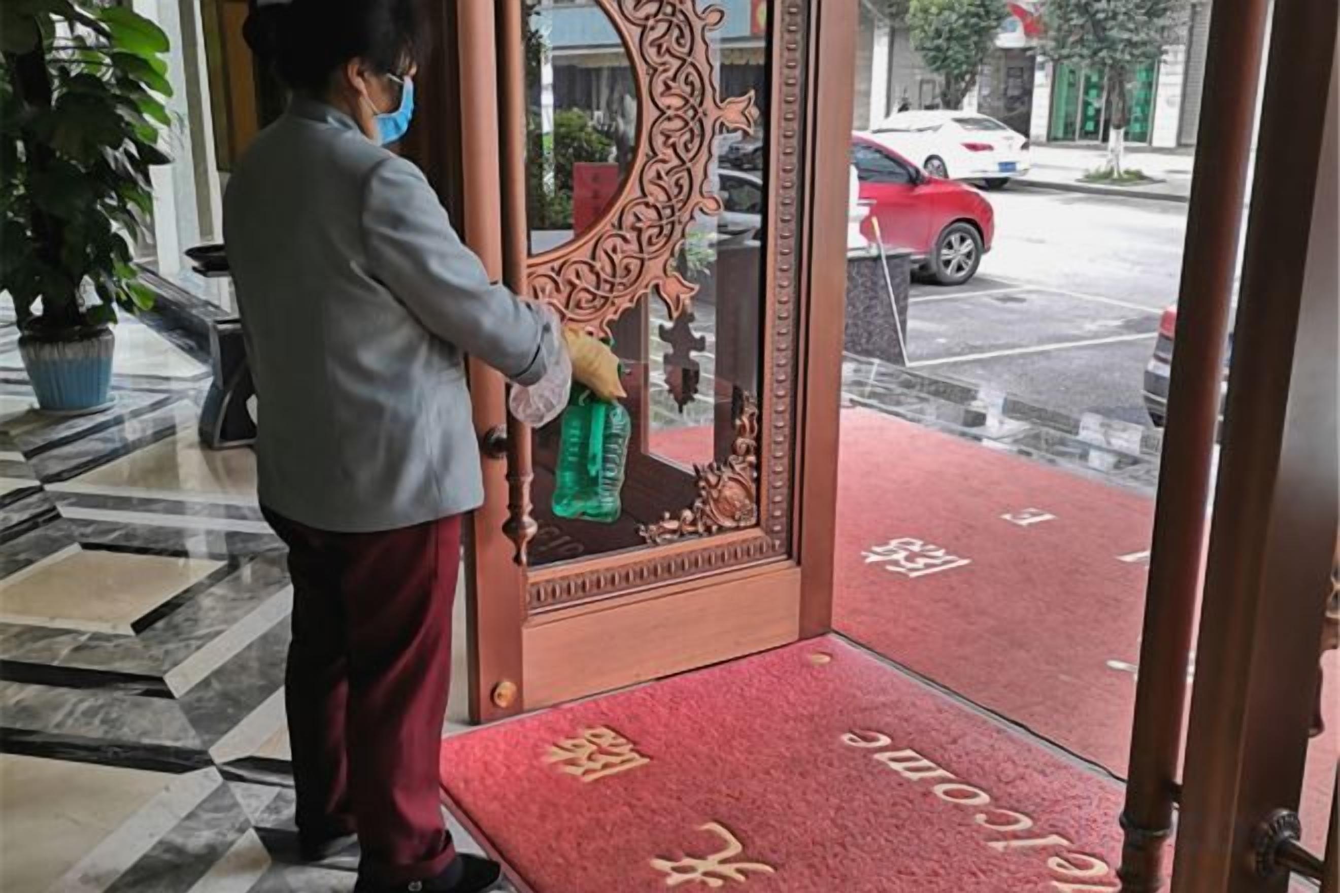 A person cleaning a glass door with a spray bottle.