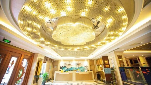 Een hotel lobby met een grote kroonluchter, receptiebalie en een vissenkom.