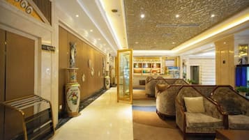 A hotel lobby with a reception desk, seating area, and a decorative ceiling.