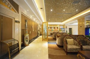 Un vestíbulo de hotel con mostrador de recepción, zona de estar y techo decorativo.