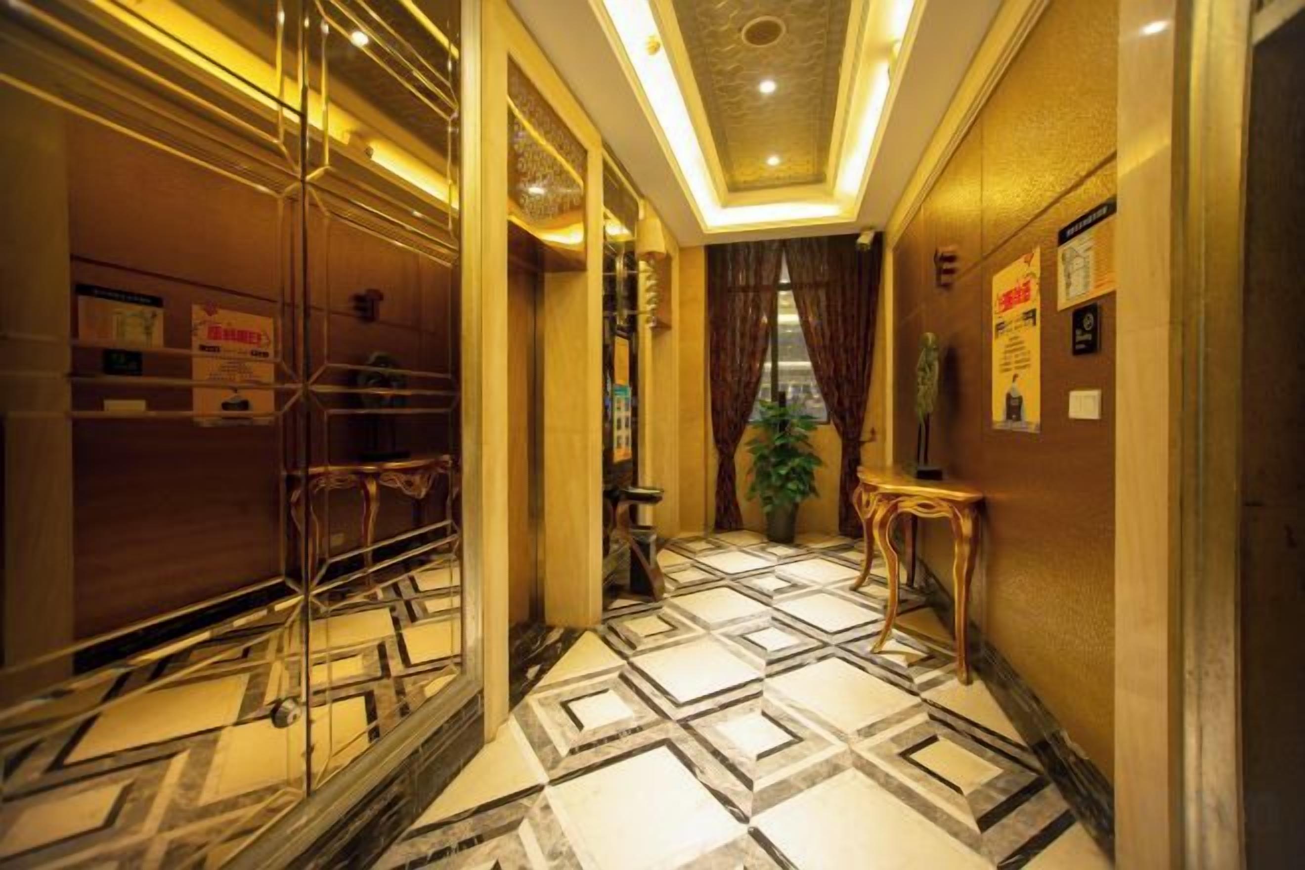 A corridor with patterned flooring, a potted plant, and a small table.