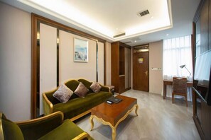 Un salón moderno con un sofá verde, una mesa de centro de madera y un escritorio con una silla.