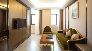 Een moderne hotelkamer met een groene bank, een houten salontafel en een televisie op een schuifdeur.