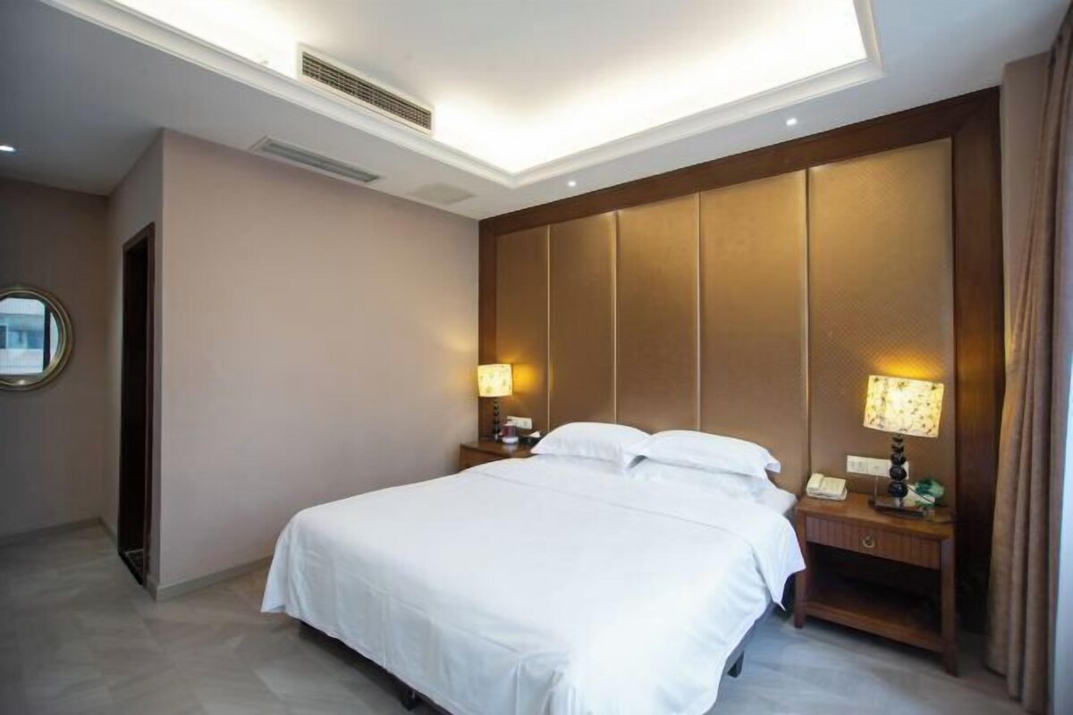 Una habitación de hotel con cama, lámparas de noche, mesita de noche y ventana.